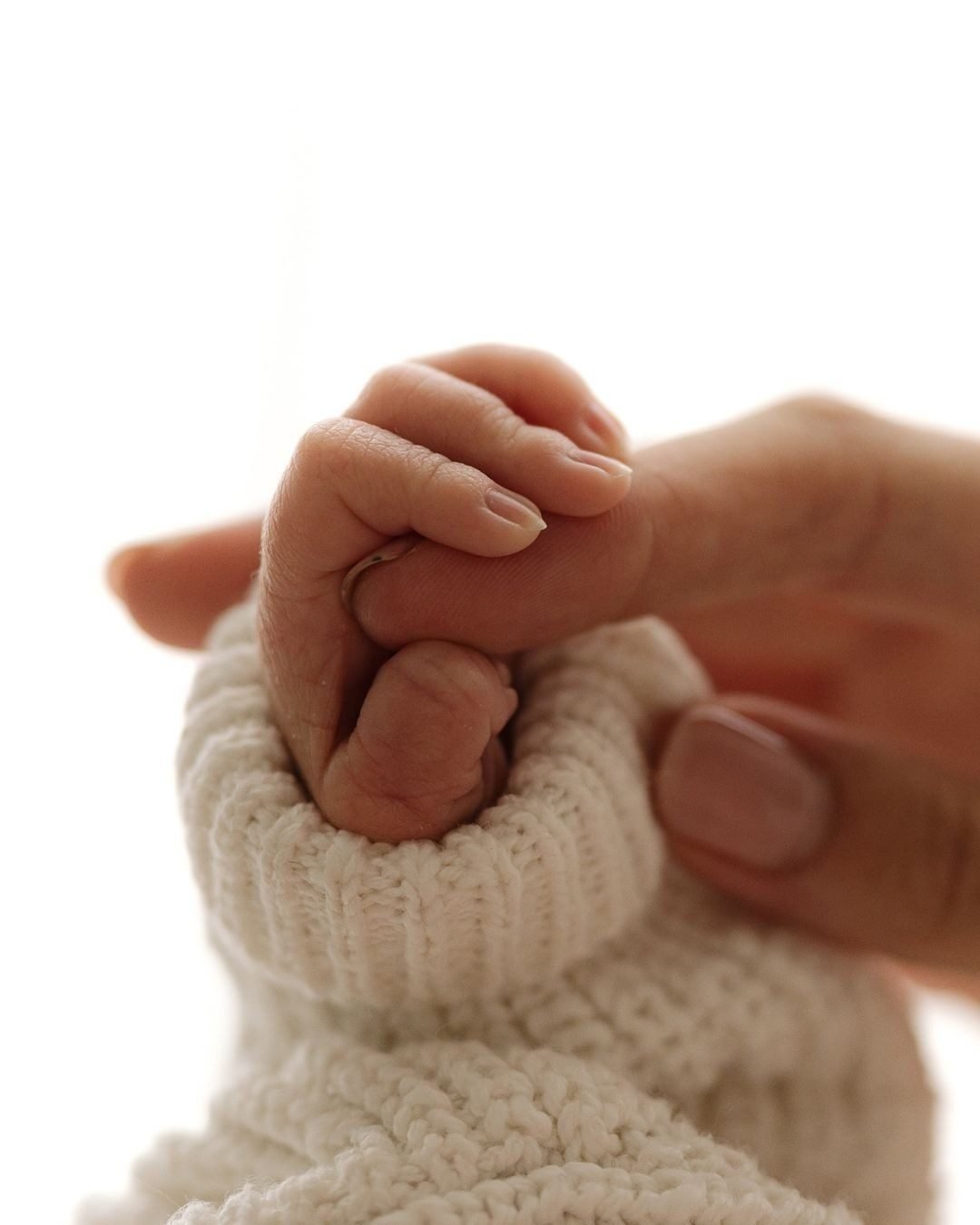 Mano de un bebé agarrando el dedo de un adulto